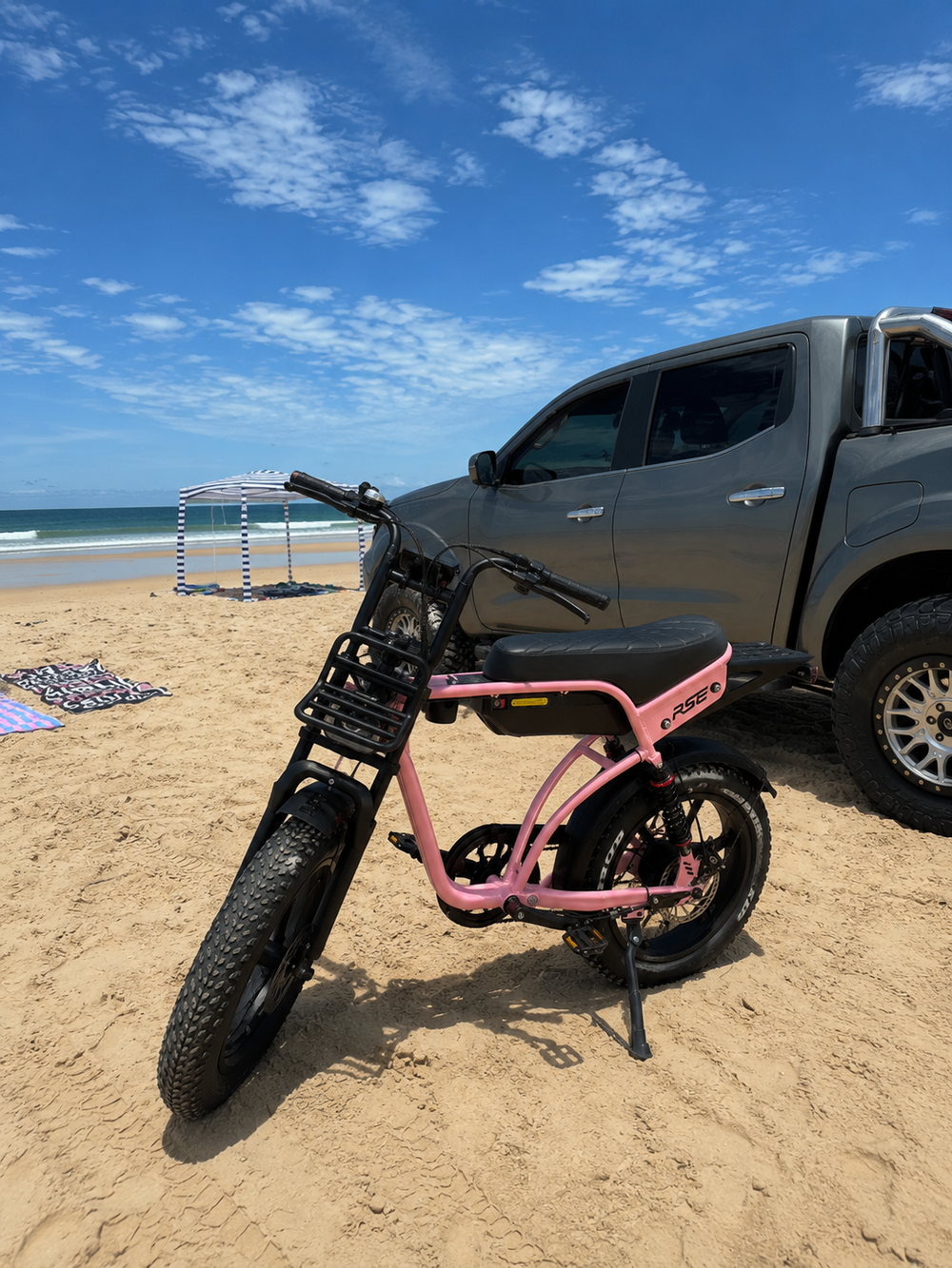 Pink Thor Pulse RSE electric bike parked on an Australian beach beside a ute with the ocean in the background.